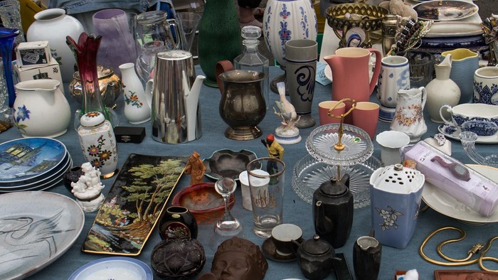 Verschiedene Vasen, Tassen und Schalen auf blauem Tischtuch.