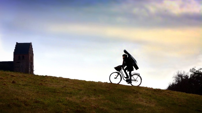 En cykelryder på en bakke ved en kirke.