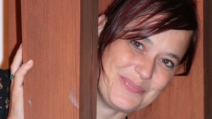 Kvinde med kort hår smiler og ser i kameraet