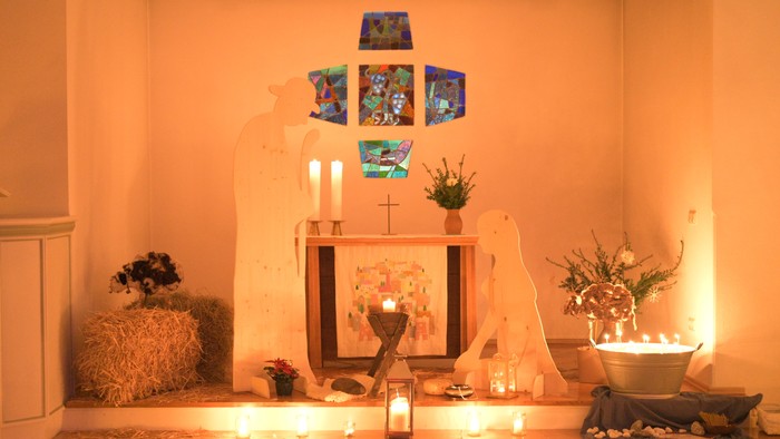 Ein geschmückter Altar mit Kerzen, Blumen und Bildern in einem warmen Raum