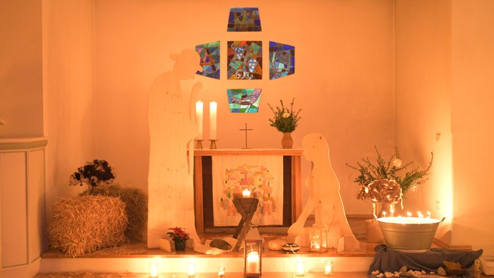 Ein geschmückter Altar mit Kerzen, Blumen und Bildern in einem warmen Raum