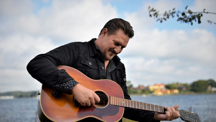 En mand spiller guitar ved vandet