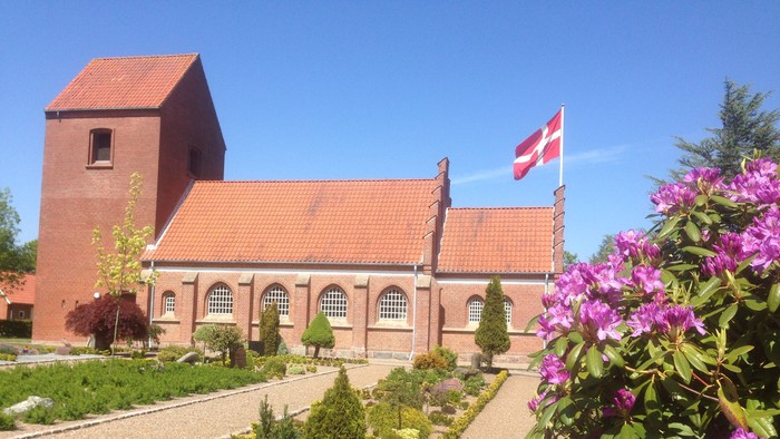 Røde kirke med flag og blomsterhave