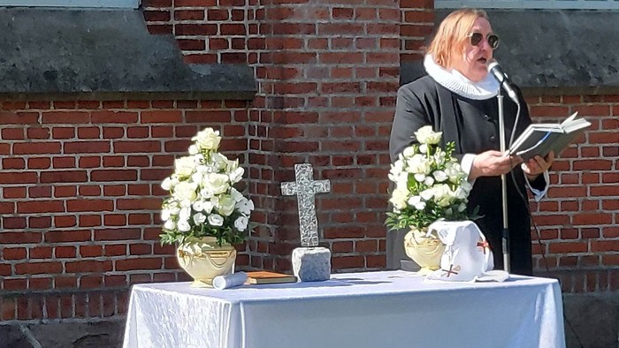 Kvinde ved alter med blomster og kors i forgrunden