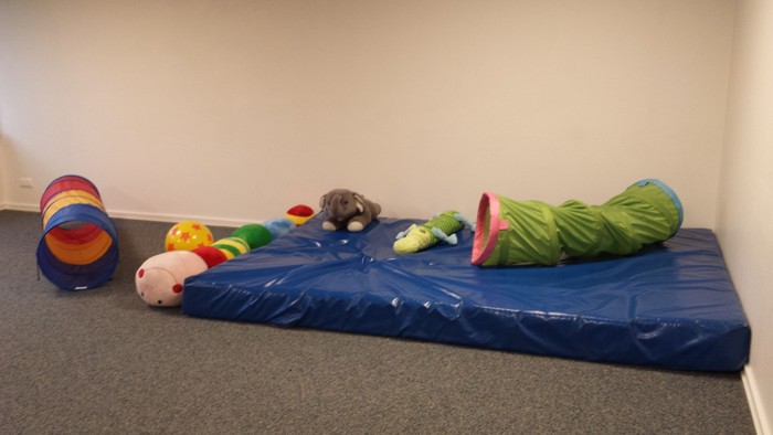 Ein blauer Matratze mit verschiedenen Spielzeugen und einer grünen Decke darauf
