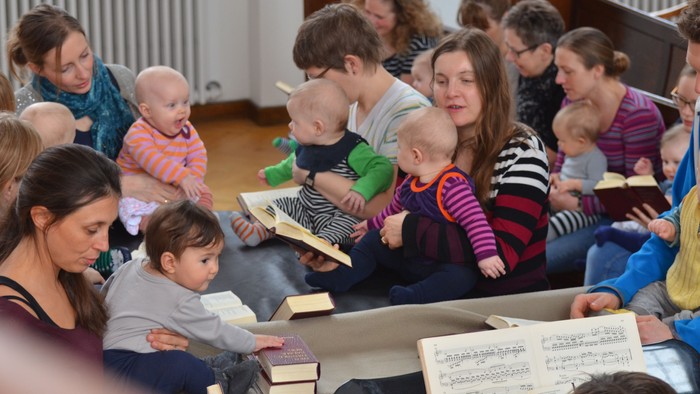 En gruppe forældre og børn sidder i en kreds og læser bøger sammen