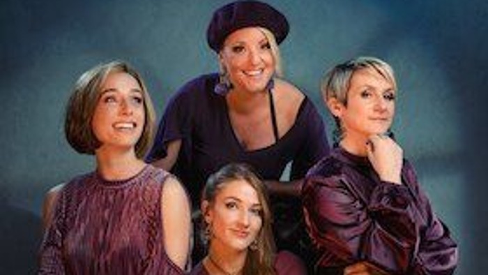 Vier Frauen in lila Kleidung posieren für ein Gruppenfoto