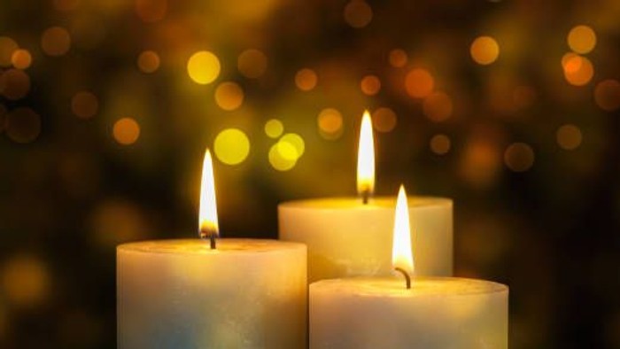 Tre lysende lysekander foran en lysete baggrund