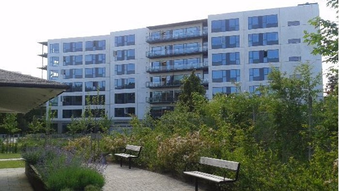 En moderne bygning med mange vinduer og en træstue med bænke.