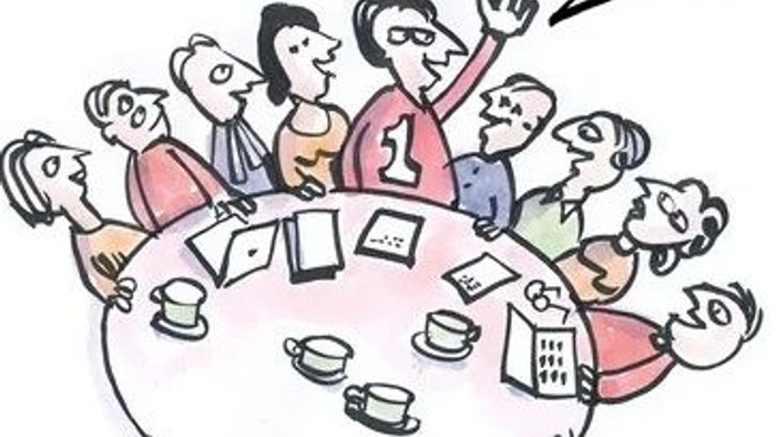 En gruppe af mennesker sidder rundt et bord og deltager i et møde.