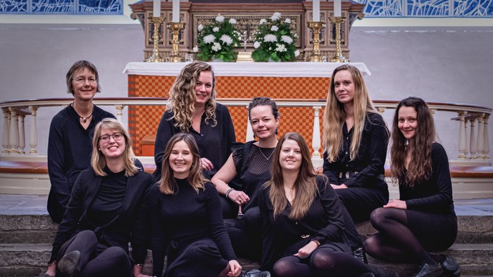 En gruppe kvinder poser i kirkeindgang med alter bagud