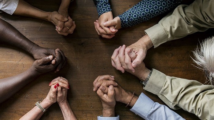 Viele Hände verschiedener Menschen sind ineinander verschränkt.