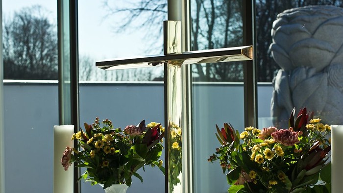 En stor guldfarvet kors med to blomsterstær med farverige blomster på hver side af et vindue