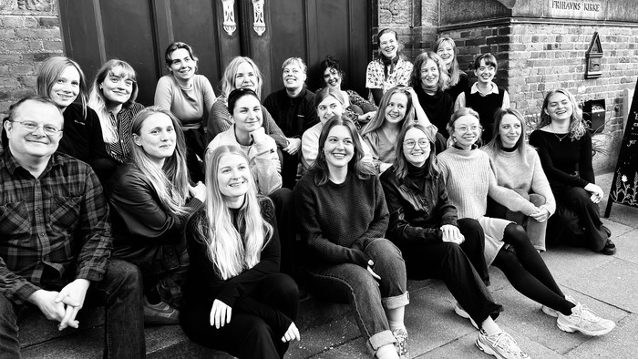 En gruppe af venner eller kolleger poserer til et glade gruppefoto.