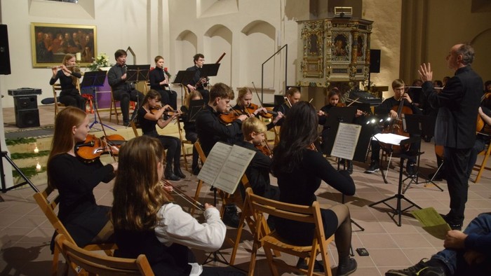 Ein Orchester probt in einer Kirche unter der Leitung eines Dirigenten