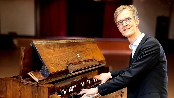 Mann in Anzug spielt auf einem großen Holzklavier