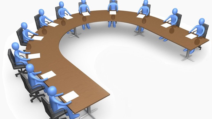 En gruppe af 12 figurer sidder i en rund konference.