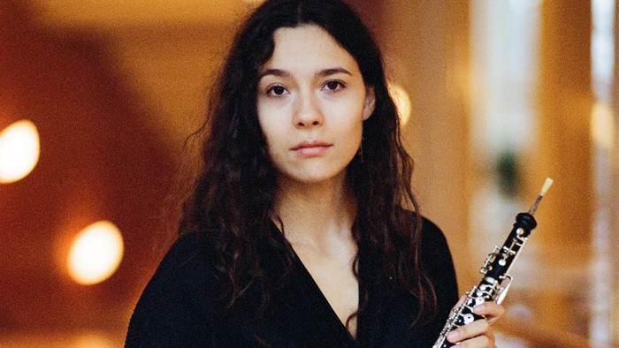 En ung kvinde med langt mørkt hår holder en klarinet.