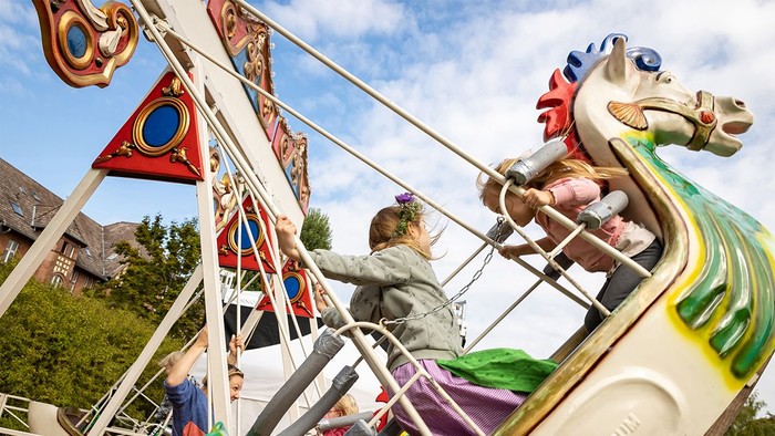 Ein Kind genießt eine Fahrt auf einem bunten Karussellpferd.