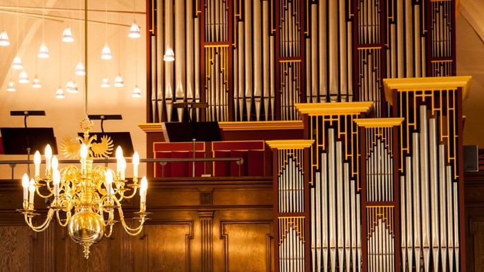 Stor kirkeorgel med gyldne detaljer og hængende lysekone