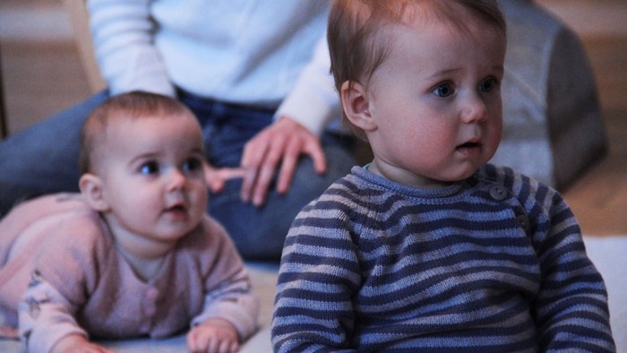 To børn ligger på gulvet foran en person.