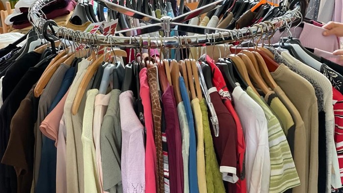 Ein Kleiderbügel mit vielen farbenfrohen Hemden und Pullovern