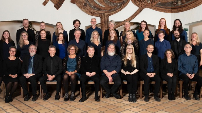 En stor gruppe af mennesker poser til et billede i en indendørs lokalitet