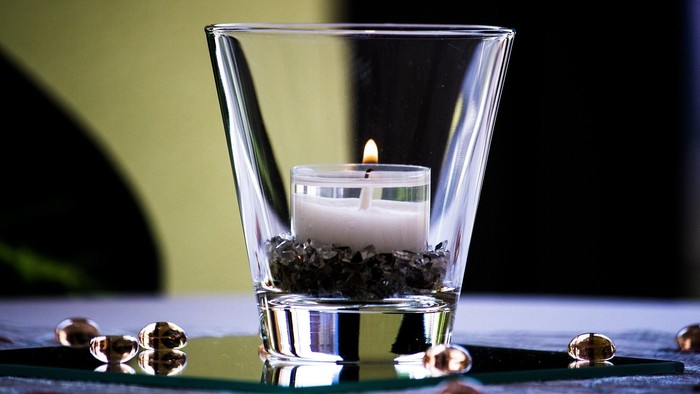 Eine Kerze in einem Glas mit Kies um sie herum.