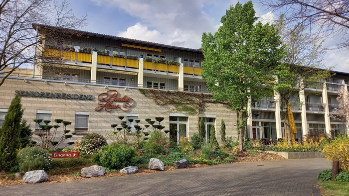 Das Bild zeigt ein modernes Gebäude mit Garten und Parkplatz.