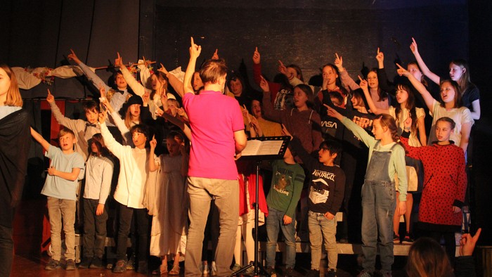 Gruppe von Menschen auf der Bühne mit erhobenen Händen