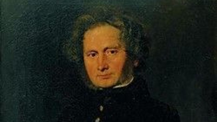 Portræt af en mand med mørkt hår og mørke klæder.