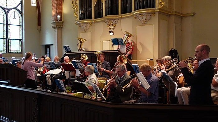 Ein Orchester spielt in einer Kirche, dirigiert von einem Mann.