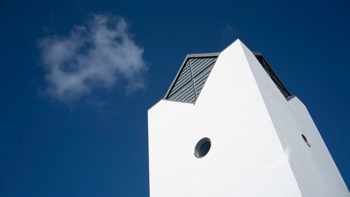 En hvid fyrtårn mod et klarblåt himmel med en lille skyer.