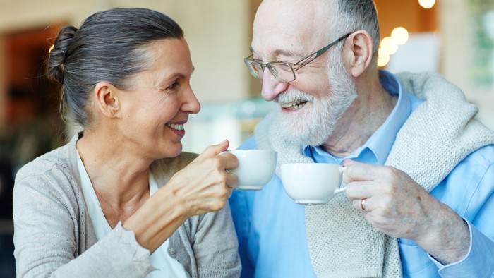 Ein älteres Paar genießt gemeinsam eine Tasse Tee und lacht.