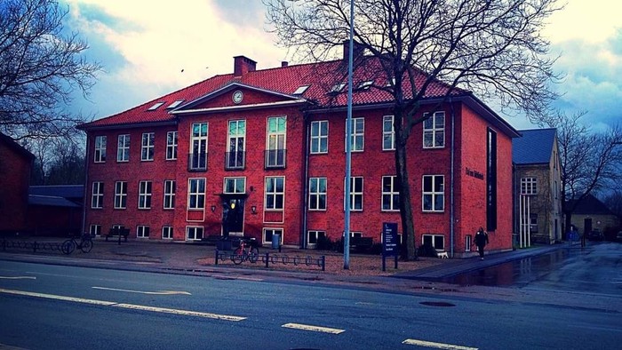 Rødt teglstenhus med rødt tag og mange vinduer.