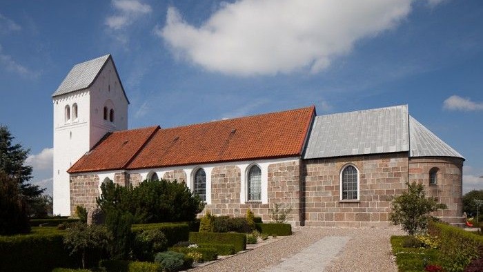 En lille kirke med klokketårn og røde tagtag.