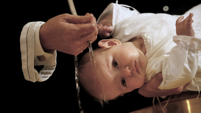 Et barn bliver døbt med vand.