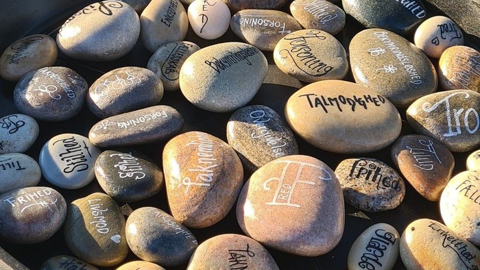 En sort bowl med sten med skriverier på.