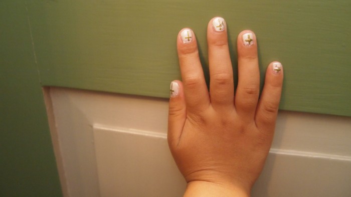 En hånd med smukke nagler med hjerteformet dekorationer.