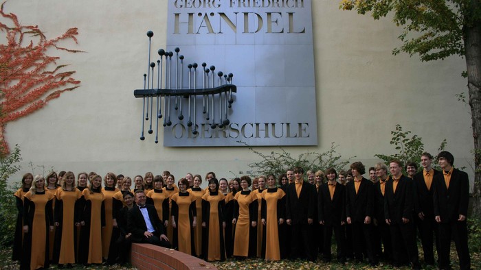 Ein Chor vor dem Georg-Friedrich-Händel-Konservatorium posiert für ein Gruppenfoto.