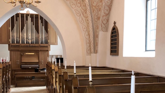 Indre del af kirke med orgel og bænke.
