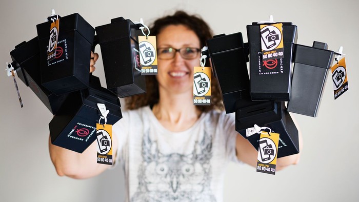 Kvinde med briller holder flere sorte pakker med logo.