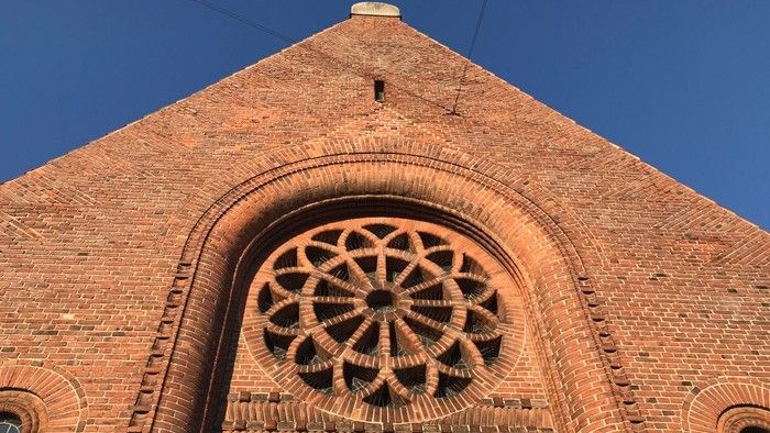 Røde mursten med indgraveret rosette-mønster i mursten over indgang.