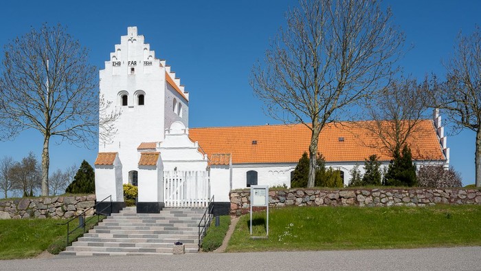 En lille, hvid kirke med orange tagtag og en smal trap til indgangen.