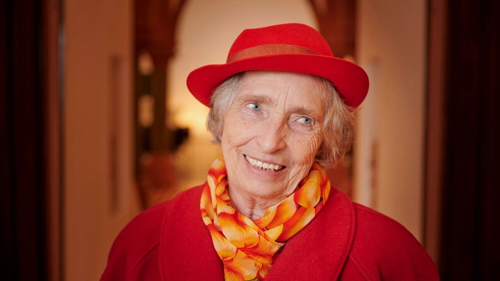 Alte Frau mit rotem Hut und Schal lächelt