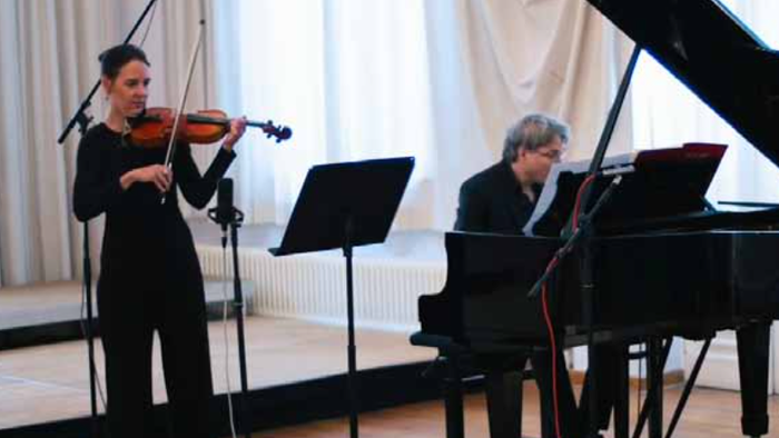 Zwei Musiker spielen Geige und Klavier auf einer Bühne