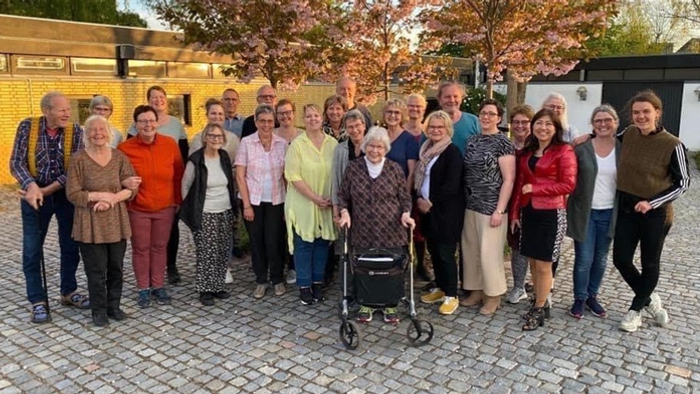 En gruppe af mennesker står sammen på en fladt murstenet plads