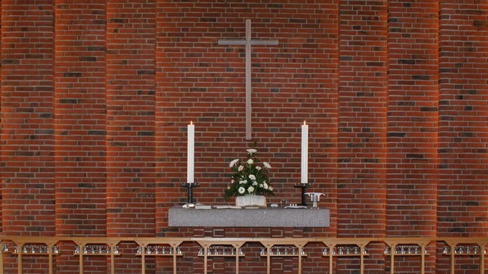 Kirkens interiør med alter, lysestake og træbænke.