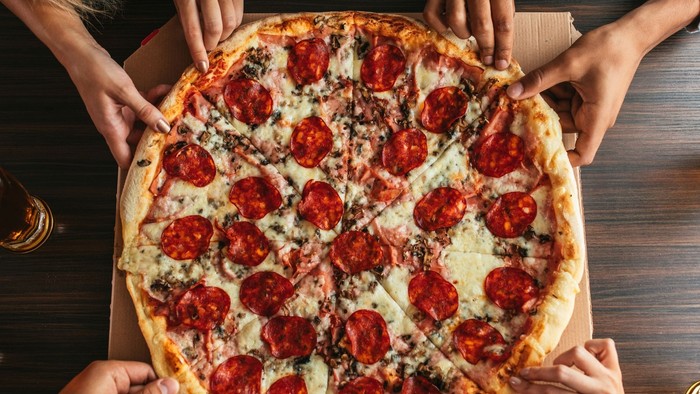 En gruppe af mennesker deler en stor pæppesuppe på et bord