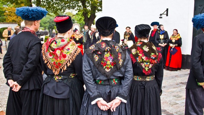 En gruppe kvinder i traditionelle kostumer og huer samles ude.